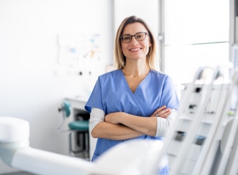 Smiling dental team member standing with arms crossed