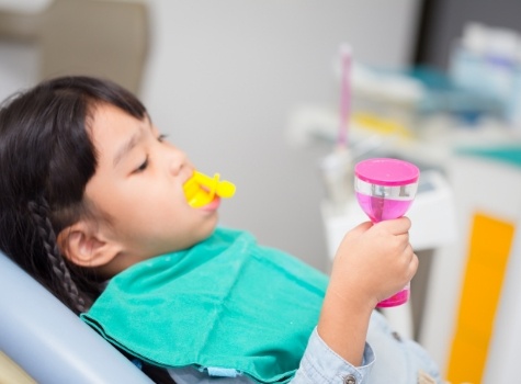 Young girl getting fluoride treatment in dental office