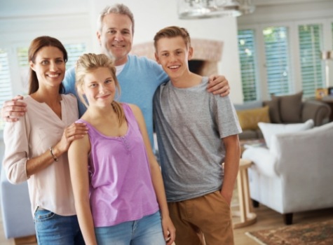 Family of four smiling in their living room