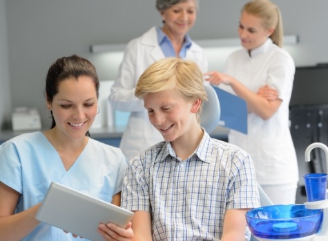 Dental team member talking to boy in dental office waiting room