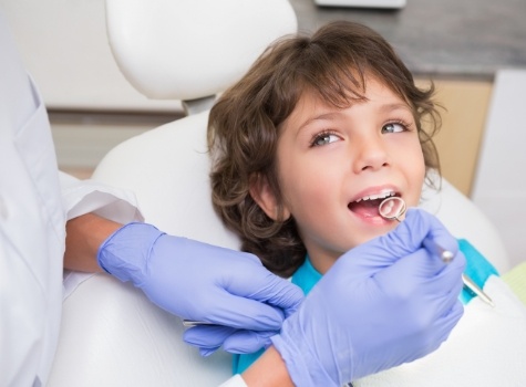 Young boy smiling with dental mirror in his mouth during dental checkup