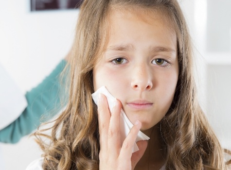 Young girl holding a tissue to her cheek