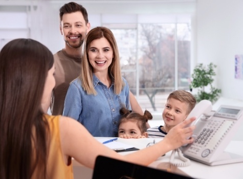 Family of four talking to dental team member at front desk