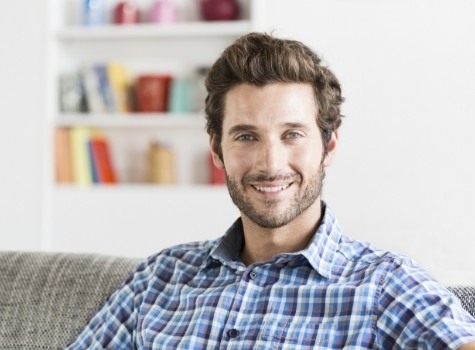 Smiling man in blue plaid shirt sitting on couch
