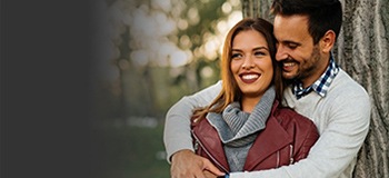 Man and woman holding each other in front of tree