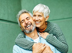 Smiling couple hugging and donning dental crowns