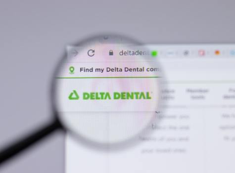 Magnifying glass in front of computer screen showing Delta Dental website