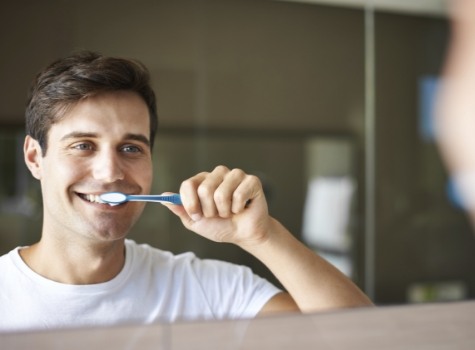 Man smiling while brushing his teeth