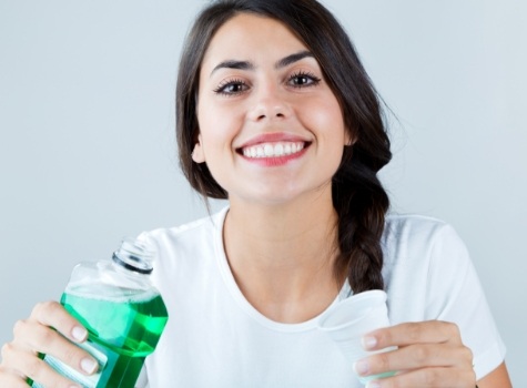 Smiling woman holding bottle of mouthwash