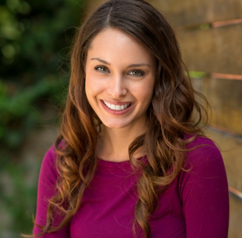 Woman in magenta blouse smiling with dental crowns in Hoover