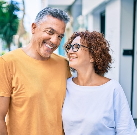 Man and woman on city sidewalk smiling with dental implants in Hoover