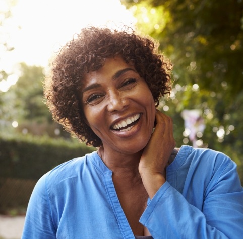 Woman in blue blouse smiling on sunny day with dentures in Hoover