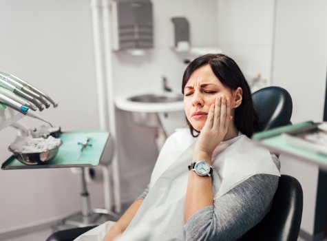 Emergency dental patient holding her cheek in pain