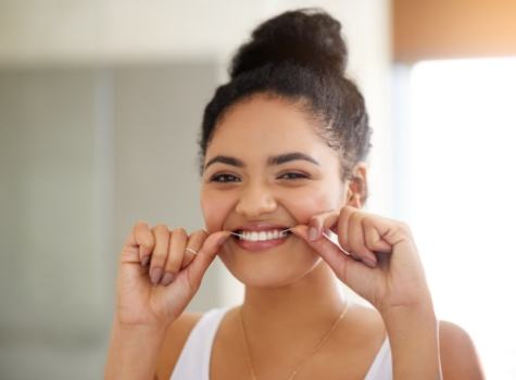 Woman grinning while flossing her teeth