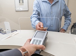 An adult man paying the cost of a tooth extraction