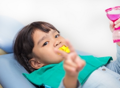 Child giving peace sign in dental chair