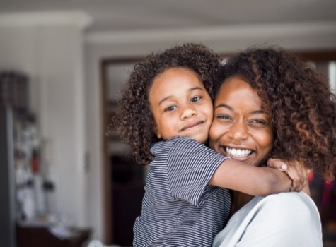 Smiling mother and child hugging at home