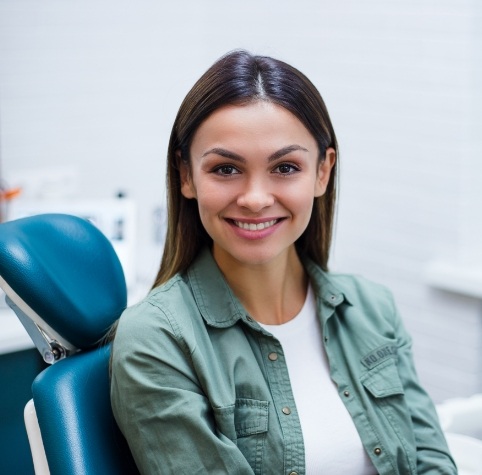 Woman in green shirt smiling during first dental appointment in Hoover