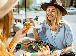 Two friends smiling while eating lunch together outside