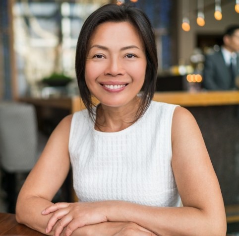 Woman smiling in coffee shop after replacing missing teeth in Hoover