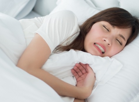 Woman grimacing while laying in bed