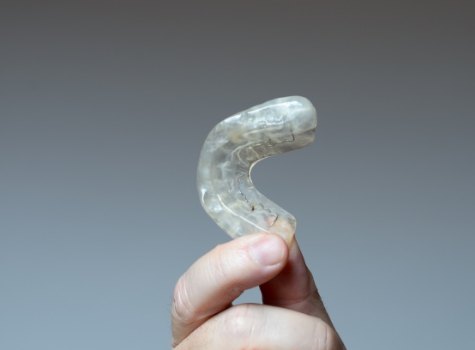 Hand holding a clear nightguard for bruxism in Hoover