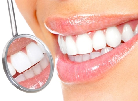 Close up of dental mirror reflecting smile with bright white teeth