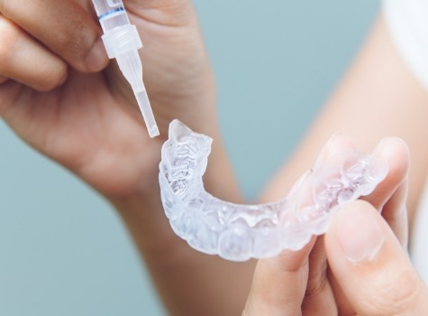 Person filling teeth whitening tray with bleaching gel