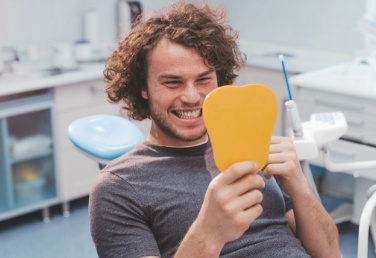 Dental patient admiring his smile after dental services in Hoover