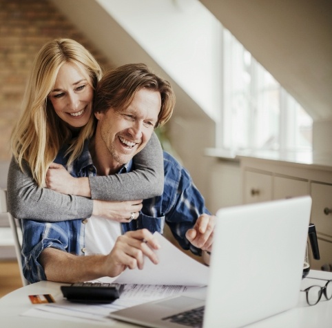 Man and woman reading dentist reviews in Hoover on laptop