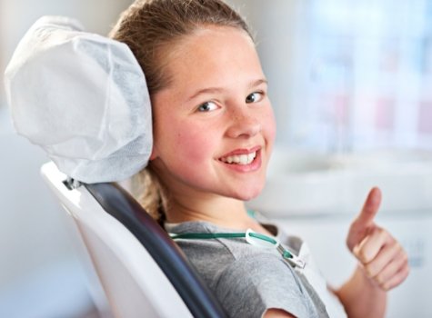 Child giving thumbs up in dental chair