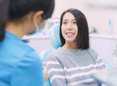 Woman in dental chair smiling at her dentist