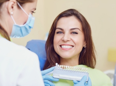 Woman grinning in dental chair after getting veneers