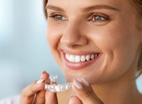 Woman smiling while holding take-home whitening tray