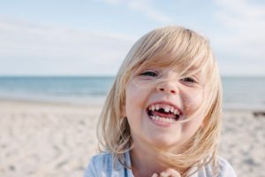 Girl missing tooth at the beach smiles after seeing Hoover children's dentist