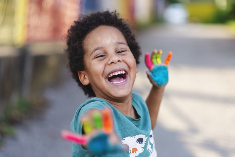 young boy smiling with painted hands