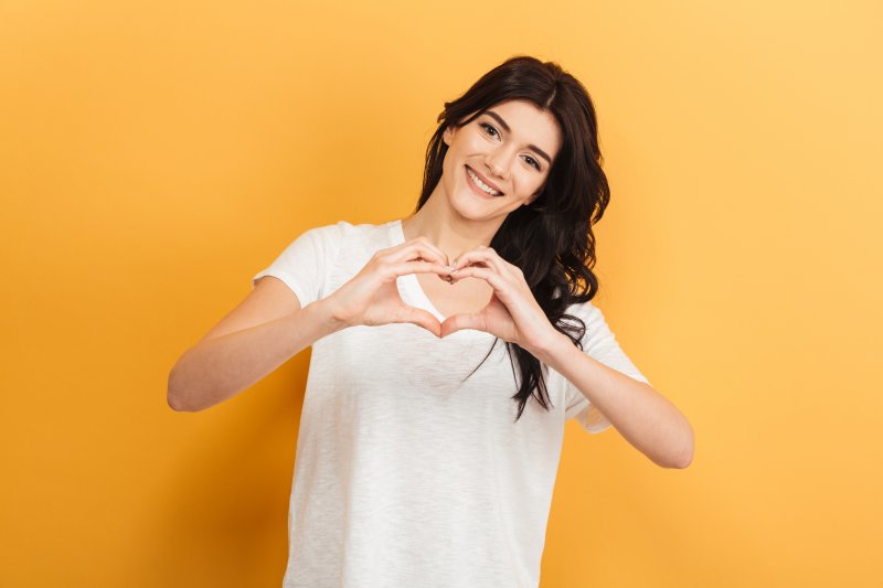 person smiling and making a heart with their hands