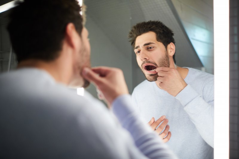 young man looking inside his mouth