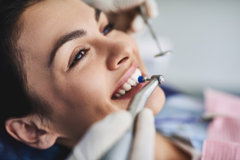 Woman getting her teeth cleaned with dental tools