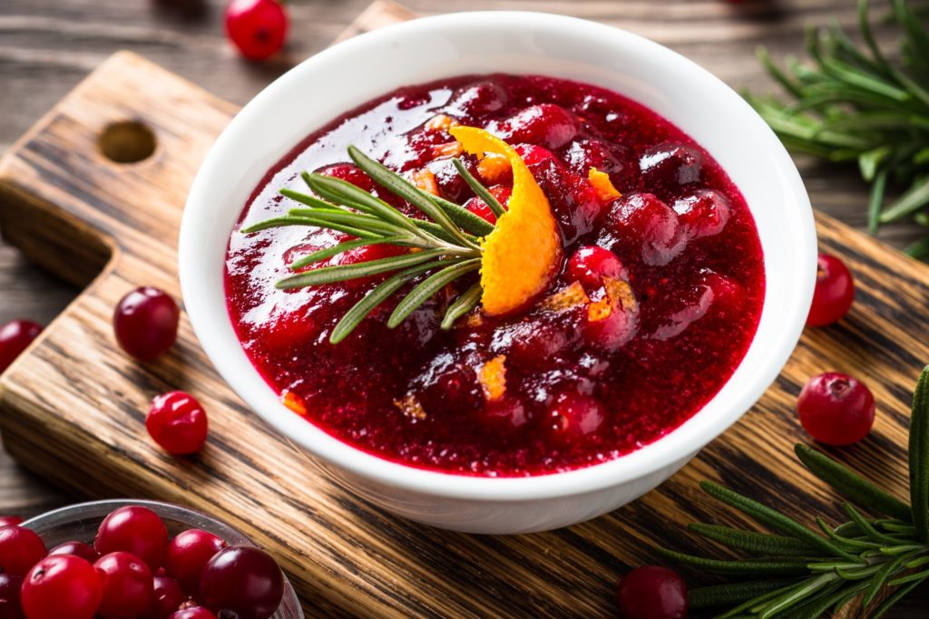 Bowl of cranberry sauce on wooden cutting board